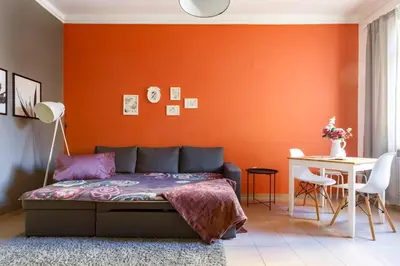 a bedroom with an orange wall with a bed and a table at Apartment 11 in Sofia