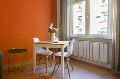 a dining room table with white chairs and a vase with flowers at Apartment 11 in Sofia
