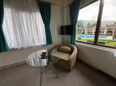 a living room with a chair and a glass table at Вила Флора Паталеница in Patalenitsa