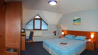 a bedroom with a bed and a desk and a window at Hotel Kibella in Sofia