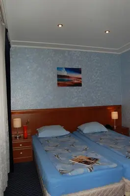 a bedroom with a large bed with blue walls at Hotel Kibella in Sofia
