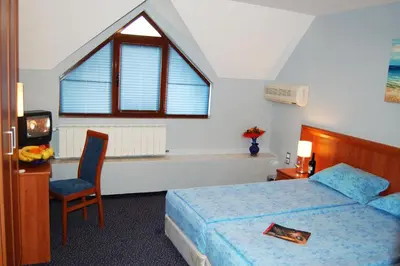 a bedroom with a bed and a chair and a window at Hotel Kibella in Sofia