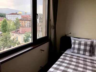 a bedroom with a bed and a window with a view at Golden Dome view Apartment in Sofia