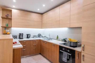 a kitchen with wooden cabinets and a stove top oven at Spacious 2-Bedroom Apartment - Ideal for Families & Groups - City Center in Sofia