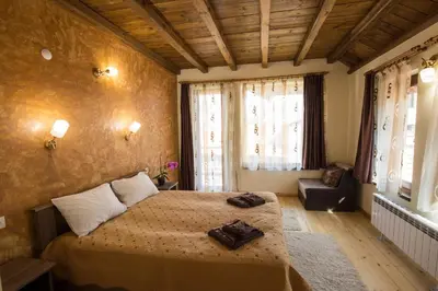 a bedroom with a bed and a couch and windows at Rupchini Houses in Bansko