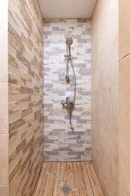 a shower in a bathroom with a stone wall at The House With The Piano in Plovdiv