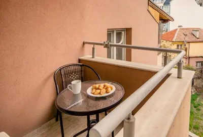 a table with a cup and a bowl of food on a balcony at Ibar Apartment & Garage in Plovdiv