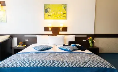 a bedroom with a blue and white bed with two pillows at Grami Hotel Sofia in Sofia