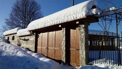 a wooden building with snow on top of it at Villa Rupcovoto in Smolyan