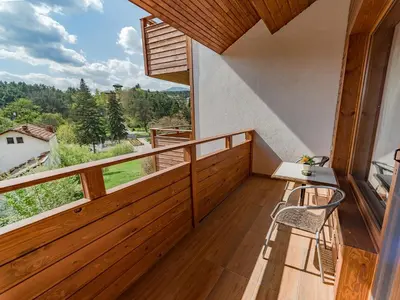 a room with a balcony with a table and chairs at Veli Hills Apartments in Velingrad