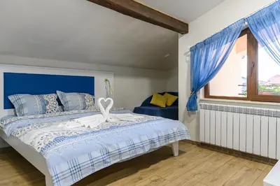 a bedroom with a bed with a blue headboard and a window at Къща за гости Мурите in Sapareva Banya