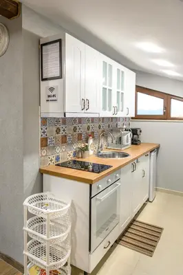a kitchen with white cabinets and a sink at Къща за гости Мурите in Sapareva Banya