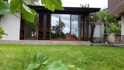 a glass house with a lawn in front of it at Kavdanski Guesthouse in Sapareva Banya
