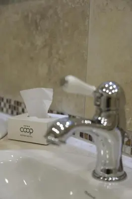 a bathroom sink with a faucet and a box of soaps at Hotel COOP, Sofia in Sofia