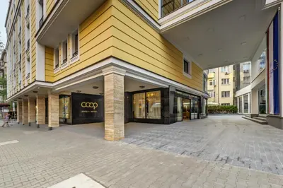 a large yellow building with a store front at Hotel COOP, Sofia in Sofia