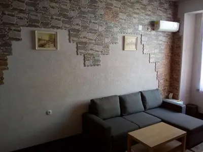 a living room with a couch and a brick wall at Vila Nova in Sandanski