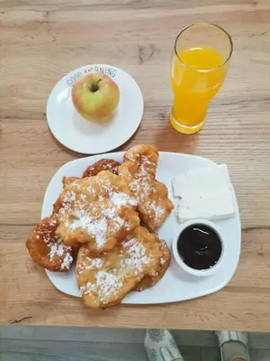 two plates of food with an apple and a glass of orange juice at Vila Nova in Sandanski