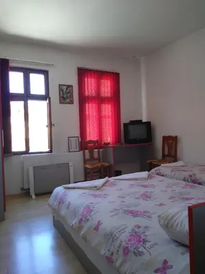 a bedroom with two beds and a tv and two windows at Guest House - Batak in Batak
