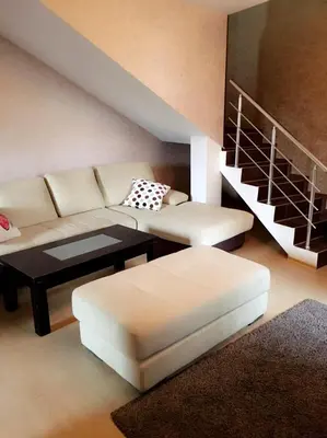 a living room with a couch and a table and stairs at Guest House Pautalya in Kyustendil