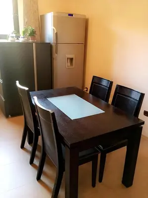 a dining room table with chairs and a refrigerator at Guest House Pautalya in Kyustendil