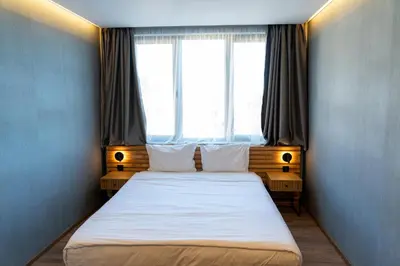 a bedroom with a large bed with two windows at Family Hotel Pak Tam in Karlovo
