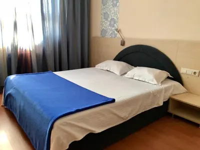 a bedroom with a large bed with a blue blanket at Hotel Astra in Sofia