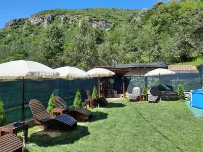 a group of chairs and umbrellas in a yard at Guest House Lazar Raykov in Ribarica