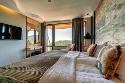 a bedroom with a large bed with a large window at Grand Hotel Murgavets in Pamporovo