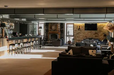 a lobby with chairs and a bar with a fireplace at Grand Hotel Murgavets in Pamporovo