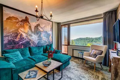 a living room with a green couch and a large window at Grand Hotel Murgavets in Pamporovo
