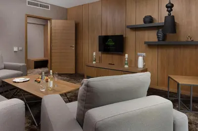 a living room with chairs and a table and a tv at Pirin Park Hotel in Sandanski