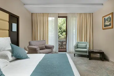 a hotel room with a bed and two chairs at Pirin Park Hotel in Sandanski