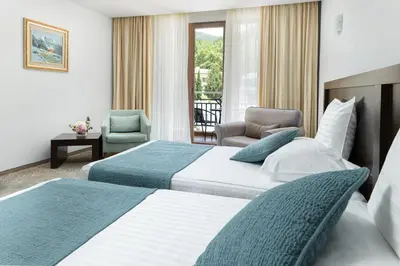 a hotel room with two beds and a chair at Pirin Park Hotel in Sandanski