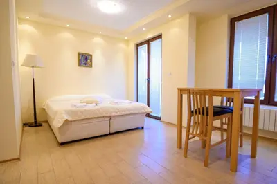 a bedroom with a bed and a table and a chair at Parklands Hotel & Pool in Bansko