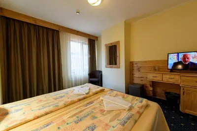 a hotel room with two beds and a flat screen tv at Kap House Family Hotel in Bansko