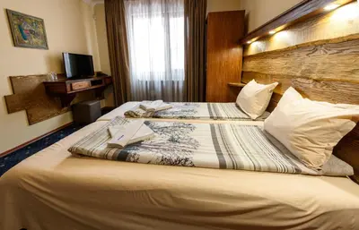 a hotel room with two beds and a television at Kap House Family Hotel in Bansko