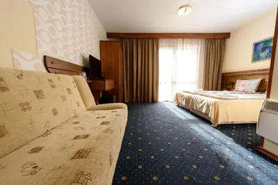 a hotel room with a couch and a bed at Kap House Family Hotel in Bansko