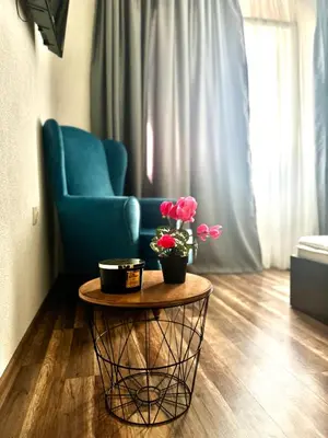 a living room with a blue chair and a table with flowers at Apartment Alex in Sandanski