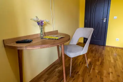 a wooden table with a vase of flowers and a chair at Guest House Villa Bozhenitsa in Bozhenitsa