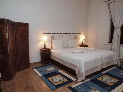 a bedroom with a bed with two lamps and two rugs at Momini Dvori Boutique Guest House in Bansko