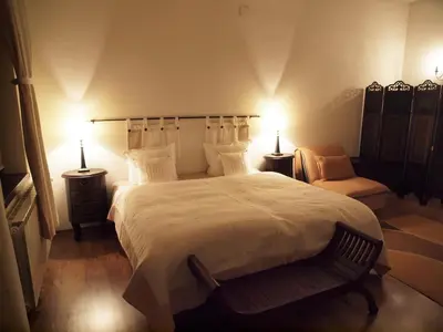 a bedroom with a large bed with two lamps and a chair at Momini Dvori Boutique Guest House in Bansko