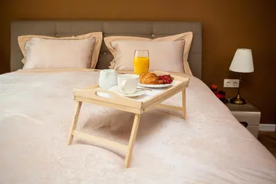 a tray of food and a glass of orange juice on a bed at Silver & Gold Apartment in Sofia