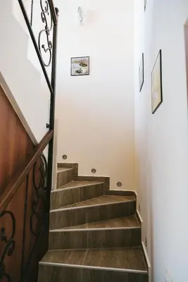 a staircase in a home with wooden stairs and white walls at Villa Maria, Complex Aleksandria in Dobrinishte