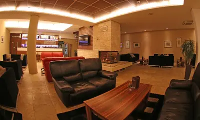 a lobby with leather furniture and a fireplace at Radina's Way Hotel in Borovets