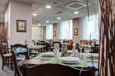 a dining room with tables and chairs and windows at Hemus Hotel Sofia in Sofia