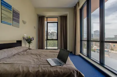 a laptop sitting on a bed in a room with windows at Hemus Hotel Sofia in Sofia