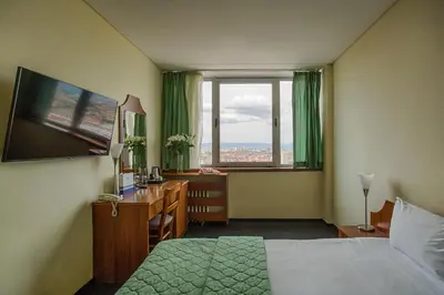 a bedroom with a bed and a desk and a window at Hemus Hotel Sofia in Sofia