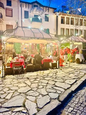a group of people sitting at an outdoor restaurant at night at Guest House Holiday in Melnik in Melnik