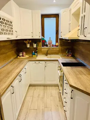 a white kitchen with white cabinets and wooden floors at Guest House Holiday in Melnik in Melnik