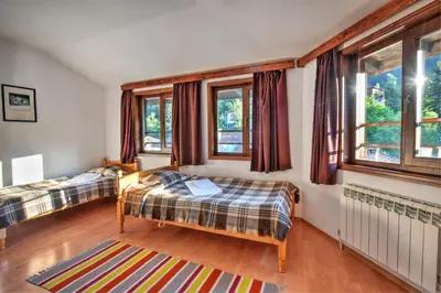 a bedroom with two beds and windows at Hotel Kalina in Shiroka Lŭka